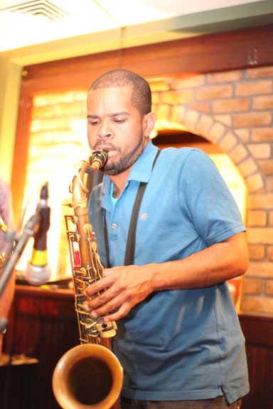 A musician playing the saxophone in a lively indoor setting.