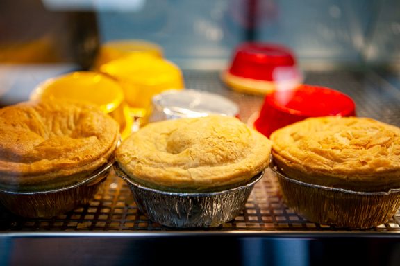Assorted pies in colourful trays showing golden baked pastry.