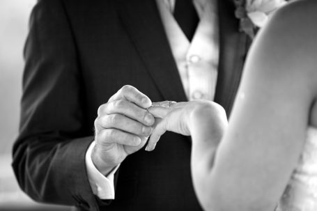 Close-up of a groom placing a wedding ring on the bride's finger.