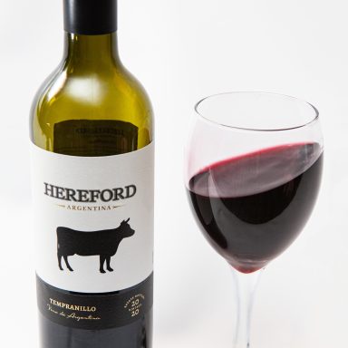 Bottle of Hereford red wine with a glass of wine beside it.