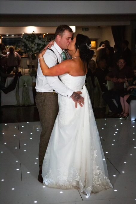 Bride and groom sharing a kiss during their first dance at a wedding reception.