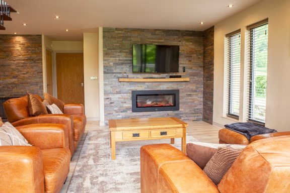 Modern living room with brown leather sofas, a wooden coffee table, and a fireplace.
