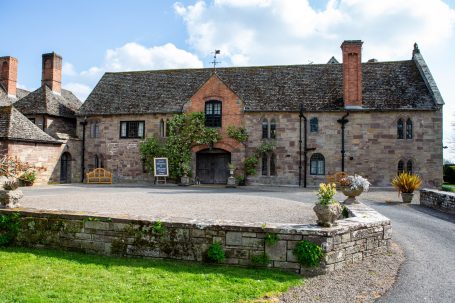 Historic stone building with a large entrance, surrounded by greenery.