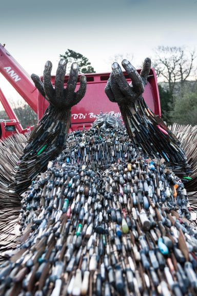 A sculpture made of collected litter, resembling arms reaching out from a pile of waste.