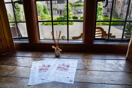 View from a window featuring a vase and sheets of paper on a wooden table.