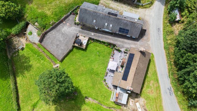 Aerial view of a rural property with multiple buildings and surrounding greenery.