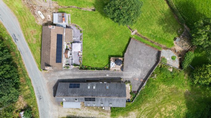 Aerial view of a property with buildings and surrounding greenery.