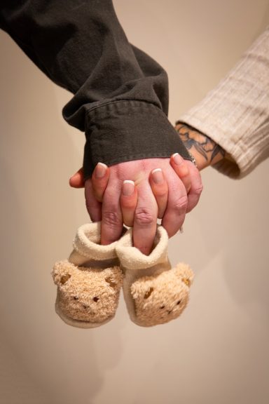 Two hands holding teddy bear slippers, symbolising love and care.