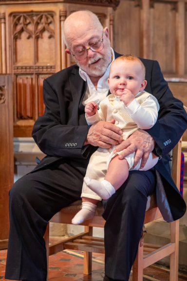 An elderly man holding a baby in a quaint indoor setting.