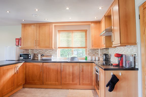 Modern kitchen with wooden cabinets, appliances, and a window letting in natural light.