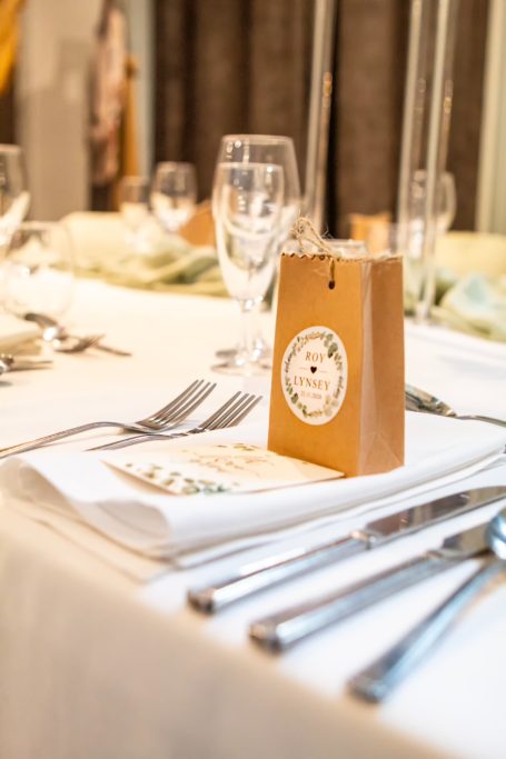 A neatly set dining table with elegant cutlery and a small gift box on a napkin.
