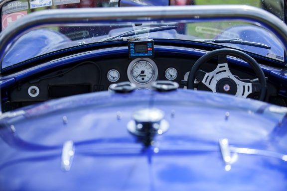 Cockpit of a blue sports car featuring a steering wheel and dashboard gauges.