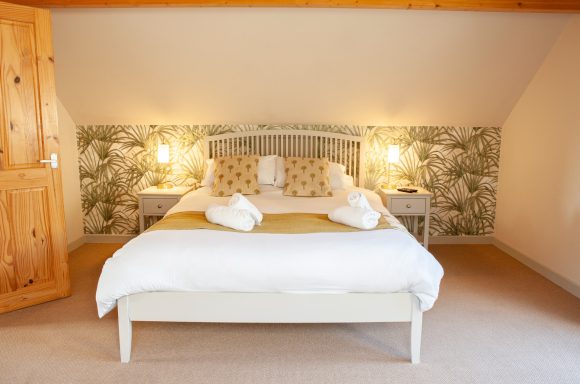 Elegant bedroom featuring a double bed, plush linens, and floral wallpaper accents.