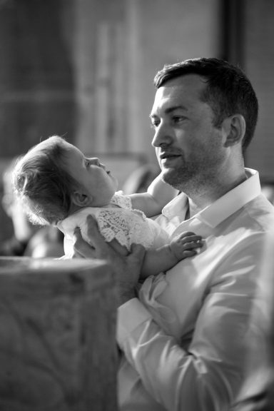 Man holding and gazing at a baby, both appearing affectionate in a soft-focus background.