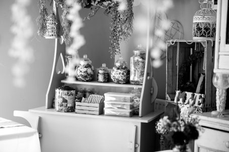 A vintage display unit with jars and decorative items, surrounded by flowers.