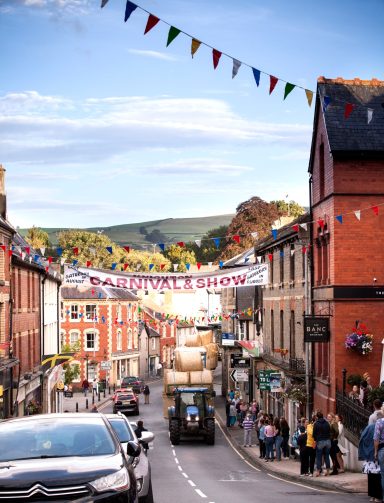 A festive street decorated with bunting and people enjoying a lively atmosphere.