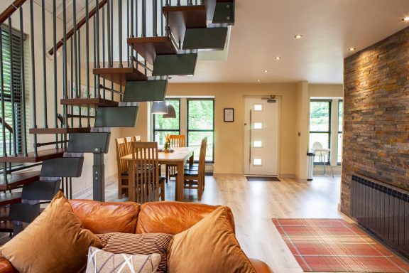 Modern open-plan living space featuring a staircase, dining area, and decorative stone wall.