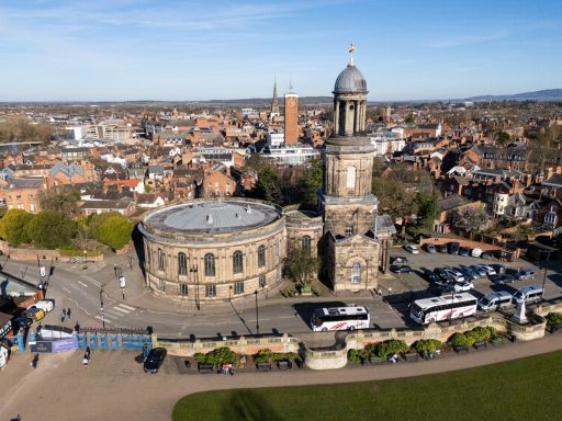 Aerial view of a historic town with a round building and clock tower.