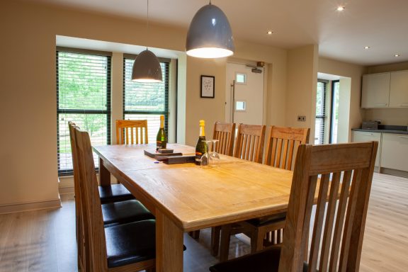 Spacious dining area with a wooden table, chairs, and two bottles of champagne.