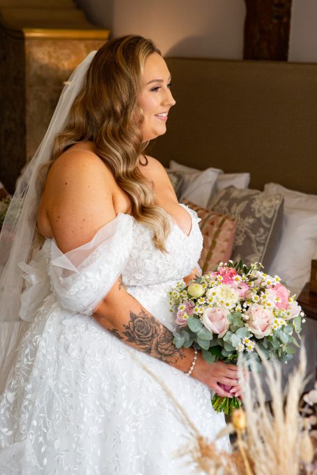 Bride in an off-shoulder wedding gown holding a bouquet of flowers.