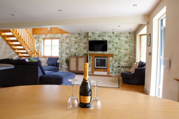 Bright living space with a bottle of champagne and glasses on a wooden table.