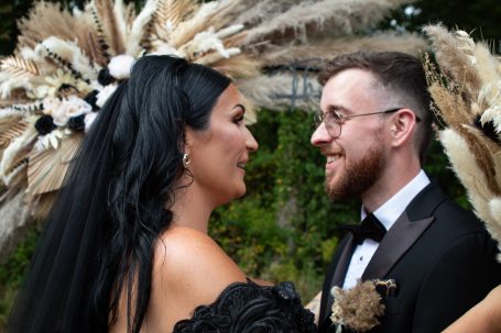 A bride and groom share a joyful, intimate moment, surrounded by floral decorations.