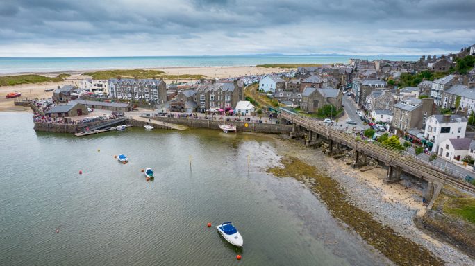 Coastal village with boats, sandy beach, and overcast skies.