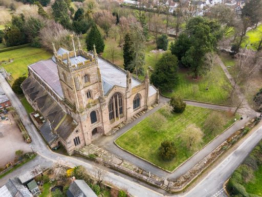 Aerial view of a historic church surrounded by greenery and trees.