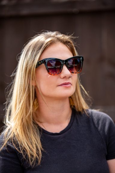 A woman with long blonde hair wearing stylish black sunglasses.