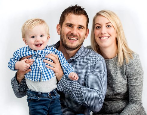 Smiling family portrait with parents holding a happy young child.