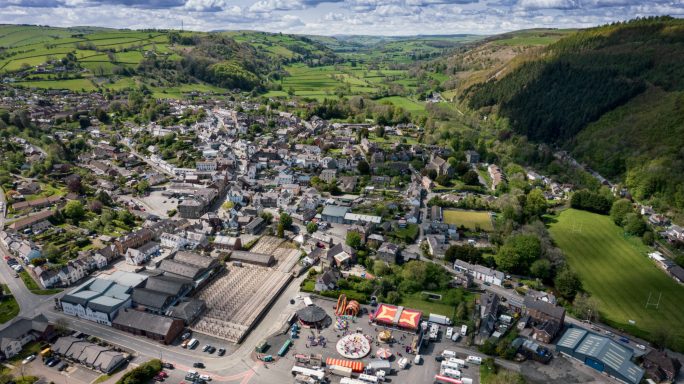 Aerial view of a small town surrounded by green hills and valleys.