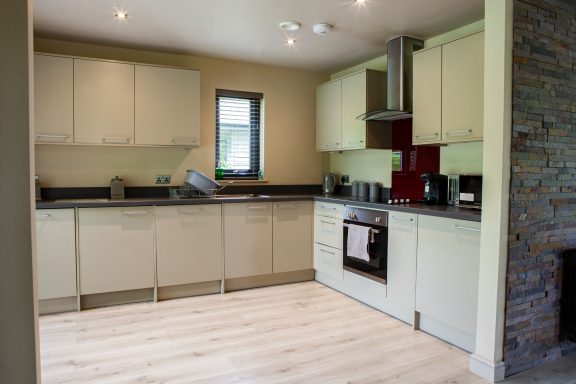 Modern kitchen with light cabinetry, black countertops, and stainless steel appliances.
