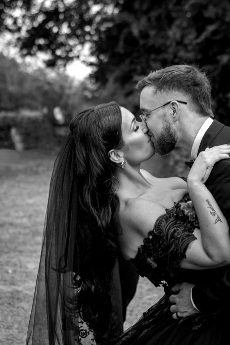 A couple sharing a kiss in a romantic outdoor setting, dressed elegantly.