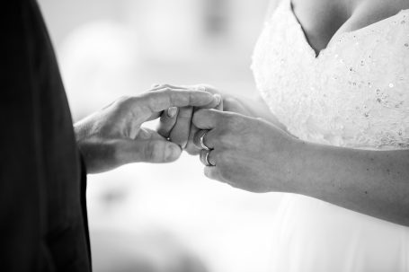 A close-up of two hands exchanging wedding rings.
