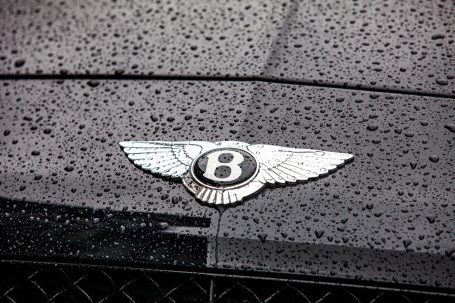 Bentley logo with water droplets on a shiny black bonnet.