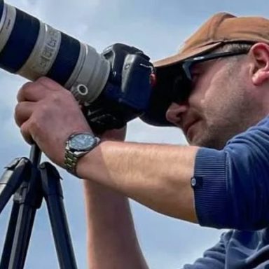 Person using a professional camera on a tripod to take photos outdoors.