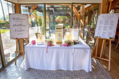 Table with a white cloth, welcome signs, floral decorations, and printed information sheets.