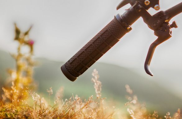 Close-up of a bicycle handlebar grip over grassy terrain.
