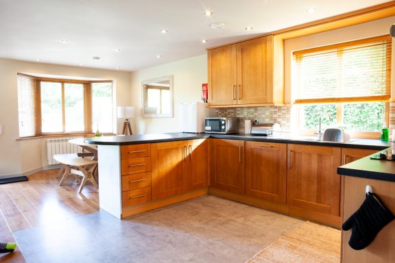 Bright kitchen with wooden cabinets, a dining table, and large windows offering natural light.