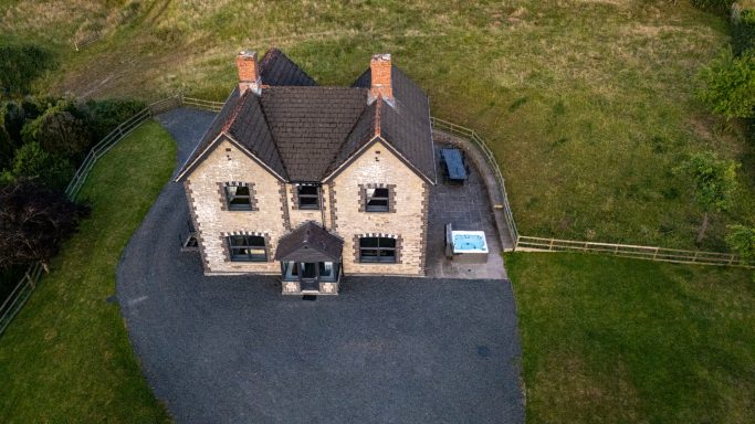 Aerial view of a spacious house with a landscaped garden and a circular driveway.