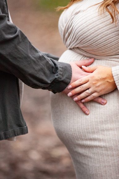A person gently touches a pregnant belly, symbolising love and anticipation.