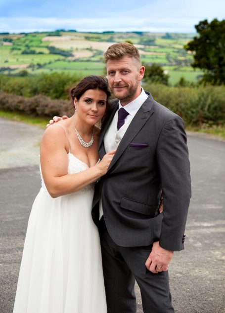 Bride and groom posing together in a scenic outdoor setting.