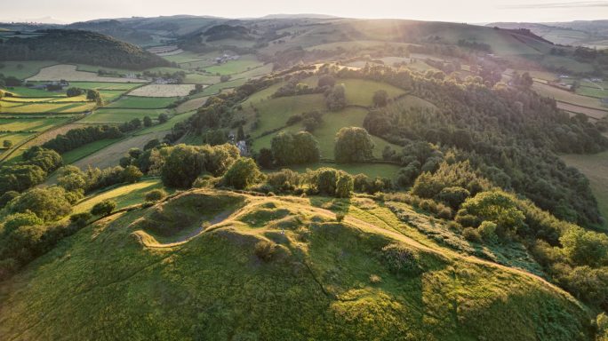 Scenic panoramic view of green hills and valleys under a warm sunlight.