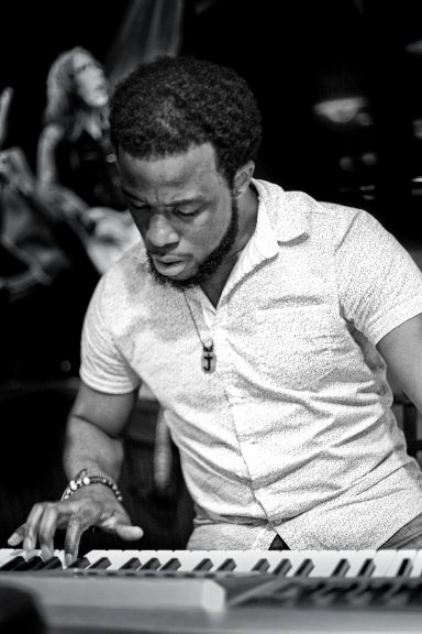 A musician playing a keyboard, focused and immersed in his performance.